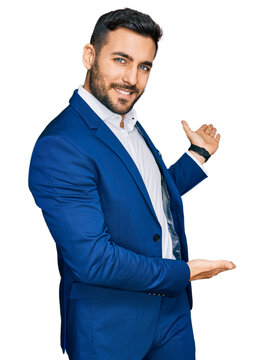 Young hispanic man wearing business jacket inviting to enter smiling natural with open hand