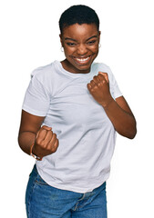 Young african american woman wearing casual white t shirt celebrating surprised and amazed for...