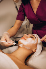 Cosmetologist applying mask on woman's face in spa salon, top view. Space for text