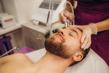 A cosmetologist is making the procedure Microdermabrasion of the facial skin in a beauty salon....