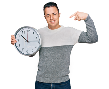 Handsome young man holding big clock pointing finger to one self smiling happy and proud