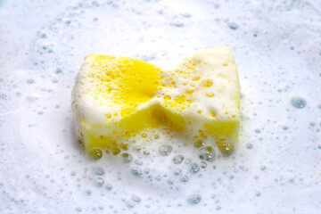 Cleaning sponge in foam of dishwashing liquid. Washing dishes concept
