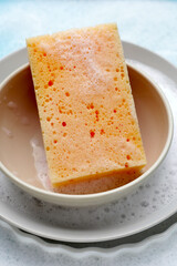 Bowl and plates with cleaning sponge in foam of dishwashing liquid. Washing dishes concept