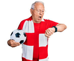 Senior man with grey hair football hooligan holding ball looking at the watch time worried, afraid of getting late