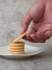 biscuits stacked on a plate and some in hand, on a gray background