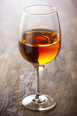 Glass of amber-colored sherry wine on wooden surface
