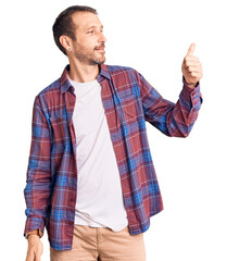 Young handsome man wearing casual clothes looking proud, smiling doing thumbs up gesture to the side