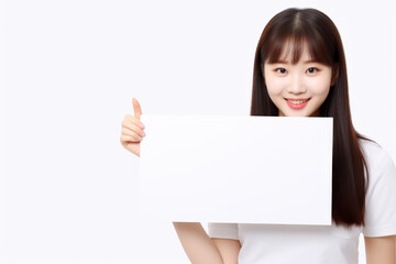 Naklejka premium Happy asian scholl girl holding blank white banner sign, isolated studio portrait.