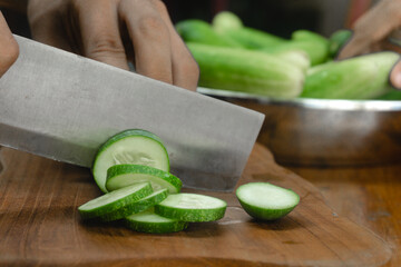 green cucumbers are cut with a knife in the kitchen. close-up green cucumbers in the kitchen hands...