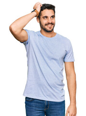 Fototapeta premium Young hispanic man wearing casual clothes smiling confident touching hair with hand up gesture, posing attractive and fashionable