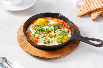 Fried egg of two eggs with bacon and tomatoes in a frying pan for breakfast