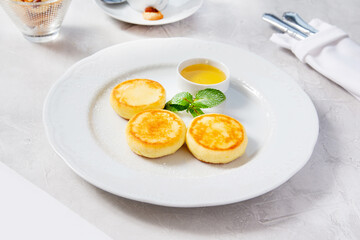 Homemade cheesecakes with honey on a white plate in a cafe, restaurant.