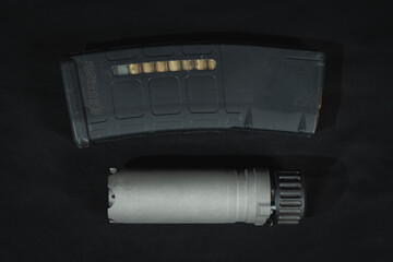 A loaded magazine with cartridges and a rifle silencer, close-up photo.