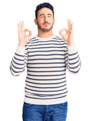 Young hispanic man wearing casual clothes relaxed and smiling with eyes closed doing meditation gesture with fingers. yoga concept.