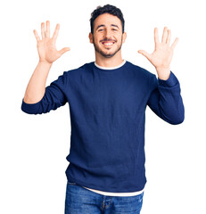Young hispanic man wearing casual clothes showing and pointing up with fingers number ten while smiling confident and happy.