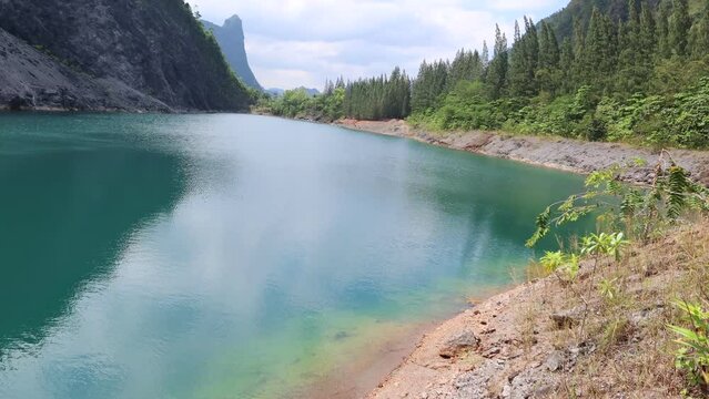 Crystal clear blue water Lake n Mountain shadow of pine tree forest on white cloud sky n tropical summer sunlight ray at Tham Thong Lang Old Stone Quarry in Phang-Nga province, Stop Motion 4 TimeLapse