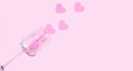 Creative flatlay composition with pink hearts and wineglass on the pink background. Valentine's day concept. Top view. Copy space. Selective focus.