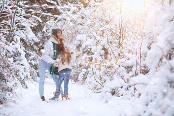 Young family for a walk. Mom and daughter are walking in a winter park.