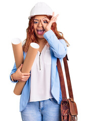 Young latin woman wearing architect hardhat holding blueprints smiling happy doing ok sign with hand on eye looking through fingers