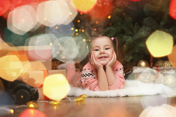 Little girl in new year's Christmas atmosphere. The girl is happy with Christmas and gifts. A child at the New Year tree with gifts.