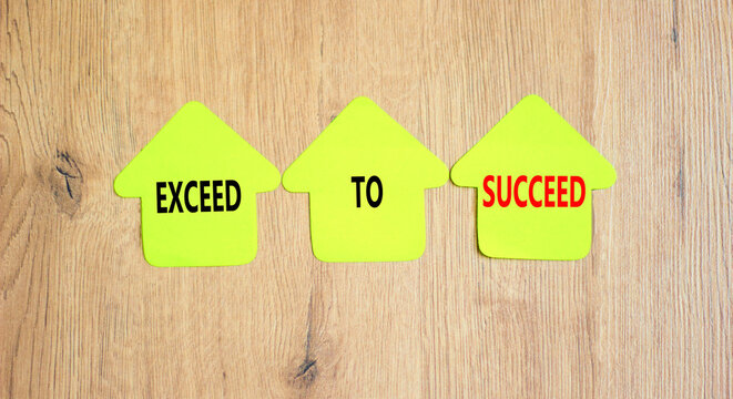 Exceed to succeed symbol. Concept words Exceed to succeed on beautiful yellow paper houses. Beautiful wooden table wooden background. Business and exceed to succeed concept. Copy space.