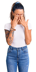 Young hispanic woman with tattoo wearing casual white tshirt rubbing eyes for fatigue and headache,...