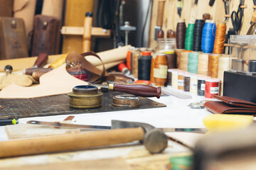 Tools and leather at cobbler workplace. Set of leather craft tools on wooden background.