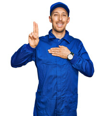 Bald man with beard wearing builder jumpsuit uniform smiling swearing with hand on chest and...