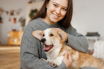 Portrait of adorable, happy smiling dog of the corgi breed. Girl playing with their favorite pet in...