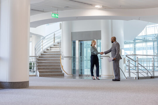 Business executives shaking hands in the entrance of a corporate office