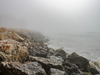 Large stones by the sea in the fog.