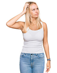 Fototapeta premium Young blonde girl wearing casual style with sleeveless shirt confuse and wondering about question. uncertain with doubt, thinking with hand on head. pensive concept.