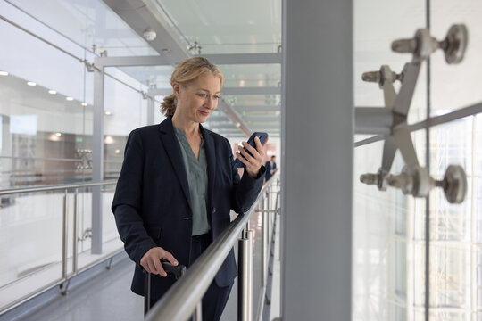 Businesswoman using smartphone in airport terminal