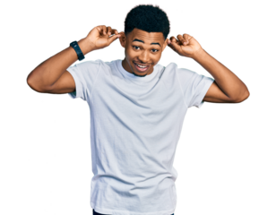 Young african american man wearing casual white t shirt smiling pulling ears with fingers, funny gesture. audition problem