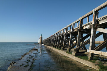 Dique junto à praia e ao porto de Capbreton com o antigo dique de madeira e um farol ao fundo