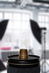 Modern digital camera lens and stack of coins in photo studio, stacked pile of coins, symbolizing...