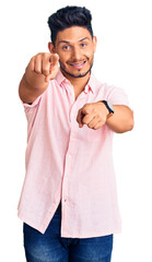 Handsome latin american young man wearing casual summer shirt pointing to you and the camera with fingers, smiling positive and cheerful