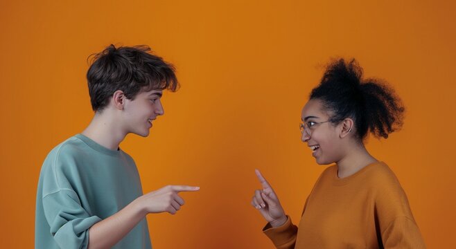 Deaf friends talk using sign language, students who smile or laugh, joking and having a good time together, the young woman is Arab, the man is Caucasian, colleages having fun telling jokes or playing