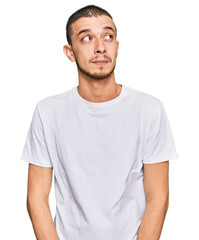 Fototapeta premium Hispanic young man wearing casual white t shirt smiling looking to the side and staring away thinking.