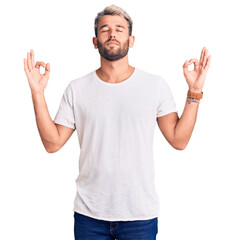 Naklejka premium Young handsome blond man wearing casual t-shirt smiling with happy face looking and pointing to the side with thumb up.