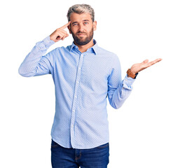 Young handsome blond man wearing elegant shirt confused and annoyed with open palm showing copy...