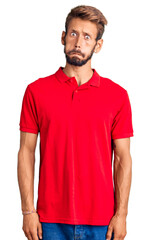 Handsome blond man with beard wearing casual clothes puffing cheeks with funny face. mouth inflated with air, crazy expression.