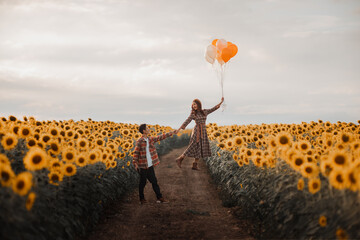 Couple in sunflower field holding balloons