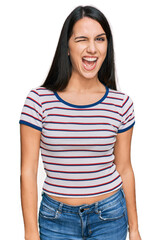 Obraz premium Young hispanic girl wearing casual striped t shirt winking looking at the camera with sexy expression, cheerful and happy face.