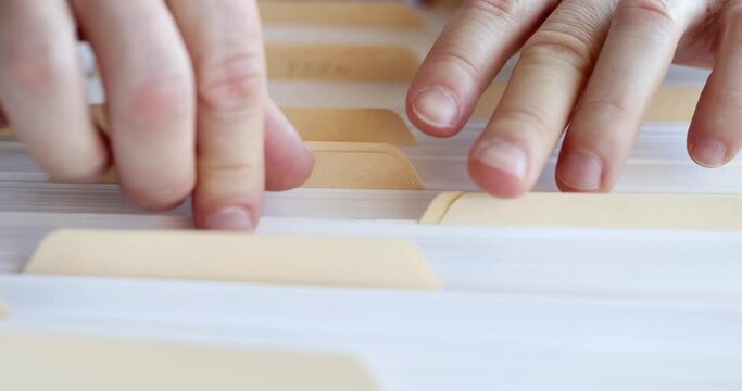 Male hands sorting through folders with business documents. Search card index of documents concept