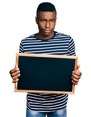 Young african american man holding blackboard depressed and worry for distress, crying angry and afraid. sad expression.