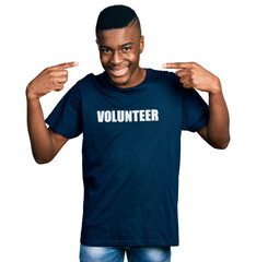 Young african american man wearing volunteer t shirt smiling cheerful showing and pointing with fingers teeth and mouth. dental health concept.