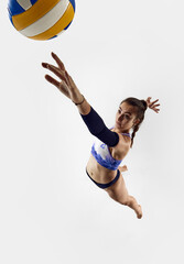 Top view. Athletic, sportive young woman, beach volleyball player in motion, hitting ball in a jump...
