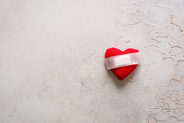 Ein rotes Herz mit einem Heftpflaster auf einem grauen rustikalen Hintergrund. Flat lay.