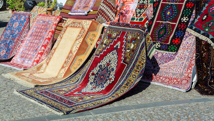 Colorful oriental carpets, sheets and other textiles in a Turkish street bazaar, traditional...